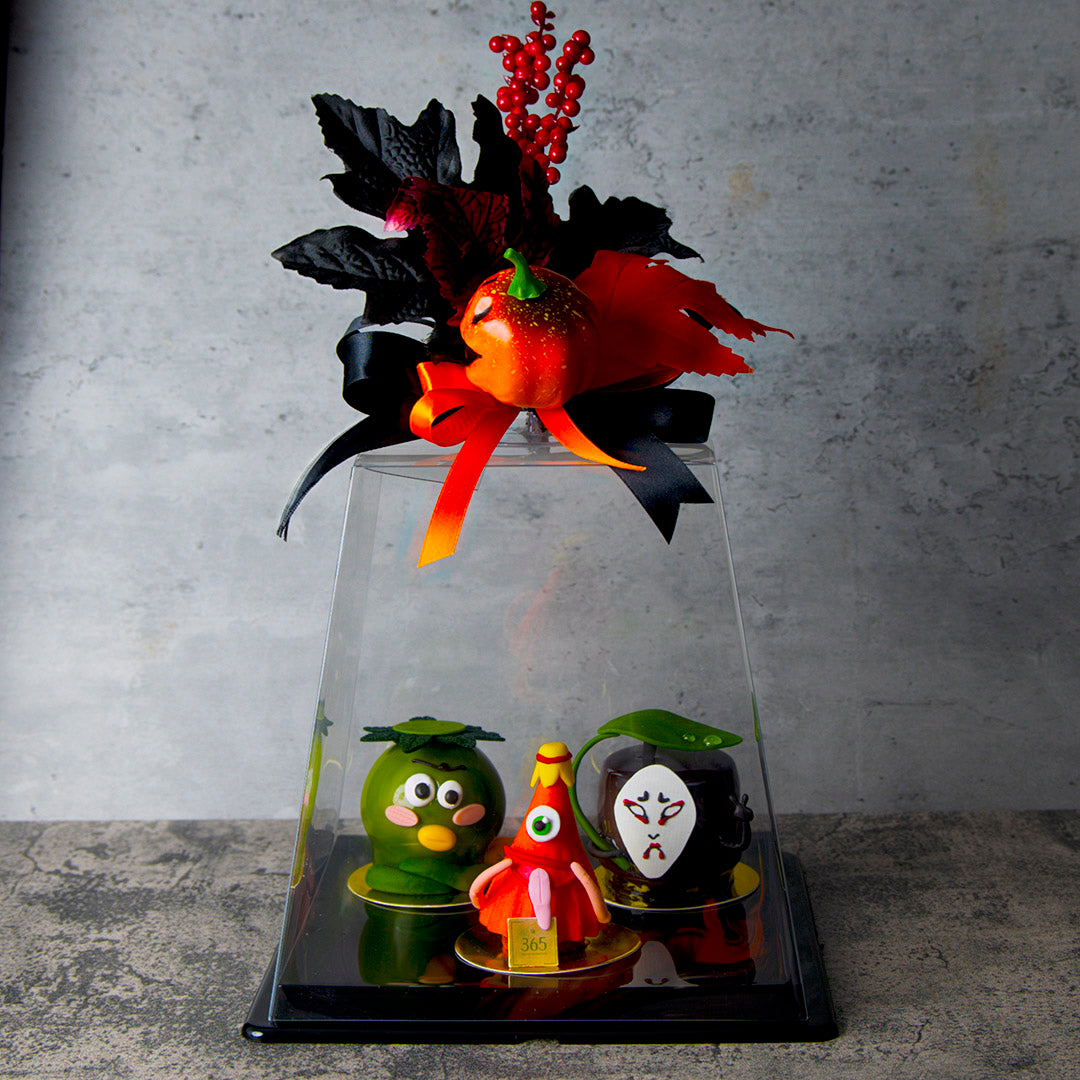 Decorative display with colorful figurines under a glass dome against a gray background
