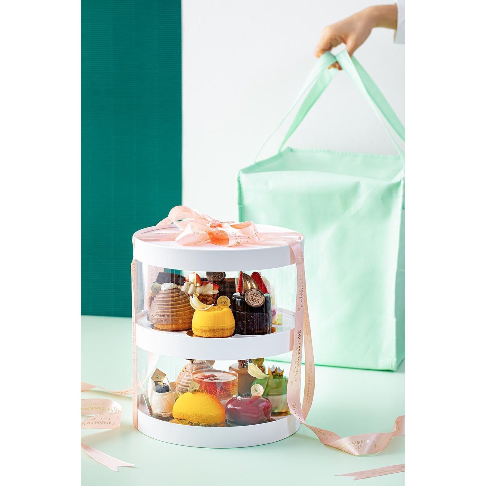 กล่องของขวัญเค้ก The Ultimate Treat Box – 13 Cakes บรรจุเค้กสุดพิเศษ 13 ชิ้น จัดเรียงอย่างประณีตในกล่องอะคริลิกใสสุดหรู ผูกริบบิ้นเพิ่มความพรีเมียม พร้อมฐานกล่องที่สามารถเขียนข้อความพิเศษได้ เค้กแต่ละชิ้นเป็นเมนูซิกเนเจอร์จากวัตถุดิบคุณภาพ เหมาะสำหรับของขวัญวันเกิด งานเฉลิมฉลอง และโอกาสพิเศษ