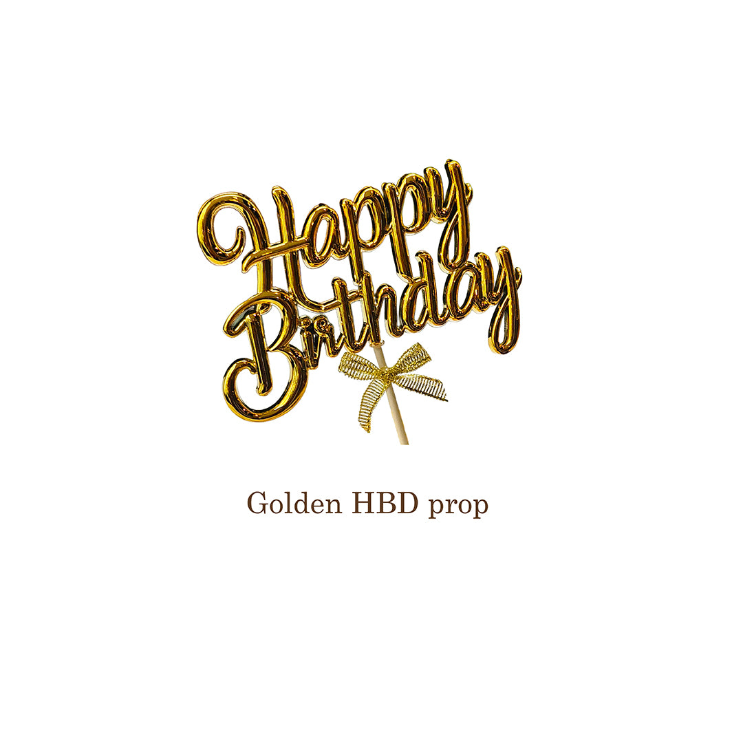Gold 'Happy Birthday' decorative prop with a bow on a white background