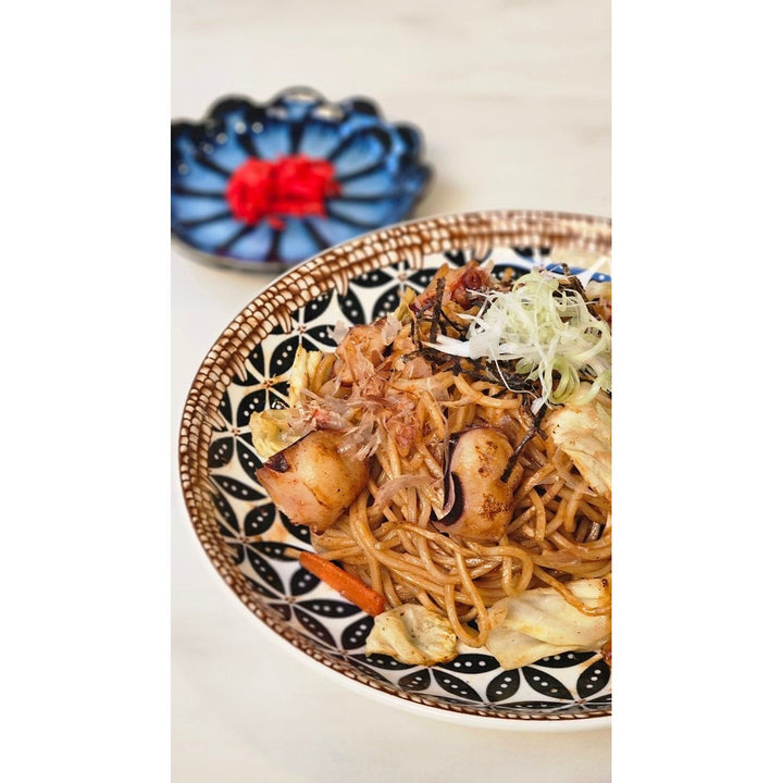 Chez Shibata 365 Authentic Japanese Yakisoba with thick, chewy noodles stir-fried in a rich, savory sauce. Served with tender squid, fresh vegetables, and topped with bonito flakes, aonori seaweed, and finely chopped scallions. Accompanied by pickled ginger for a perfectly balanced Japanese flavor. 🍜✨