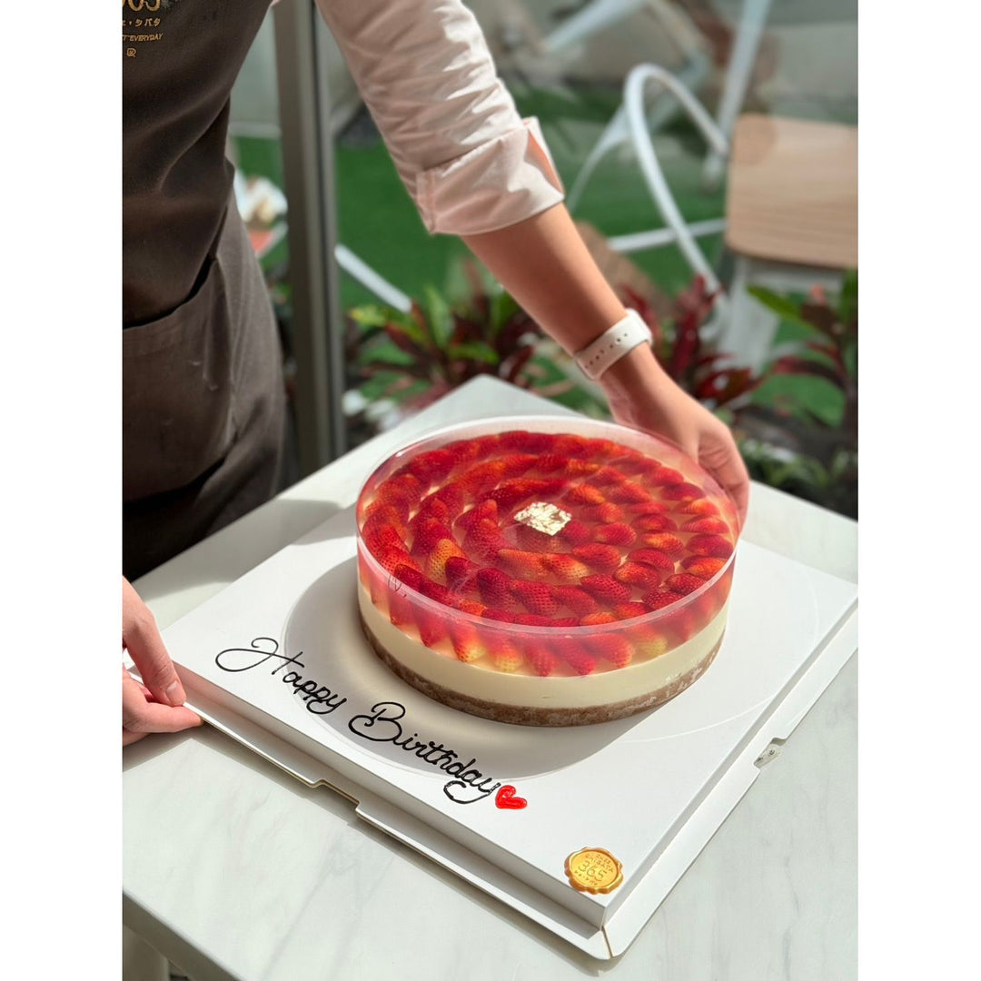 Strawberry cake on a 'Happy Birthday' card with a person's hand holding it.