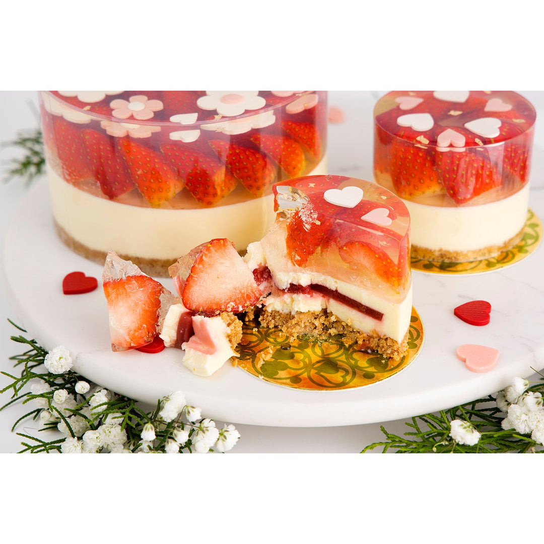 Strawberry-flavored dessert with a slice cut out on a white plate, surrounded by flowers. strawberry cheese cake chez shibata365