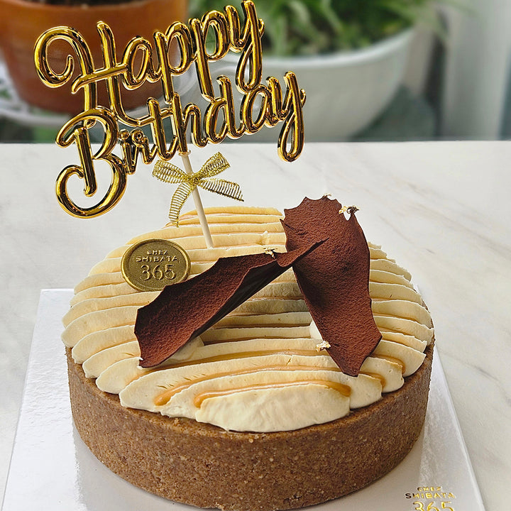 Birthday cake with a 'Happy Birthday' topper on a white surface.