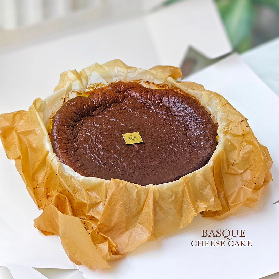 Basque Cheesecake จากร้าน Chez Shibata 365 ชีสเค้กหน้าไหม้สูตรต้นตำรับ สไตล์สเปน หน้าฉ่ำเข้มข้น หอมกรุ่น เสิร์ฟในกระดาษอบสีทองอ่อนพร้อมป้ายทอง 365 บนหน้าเค้ก